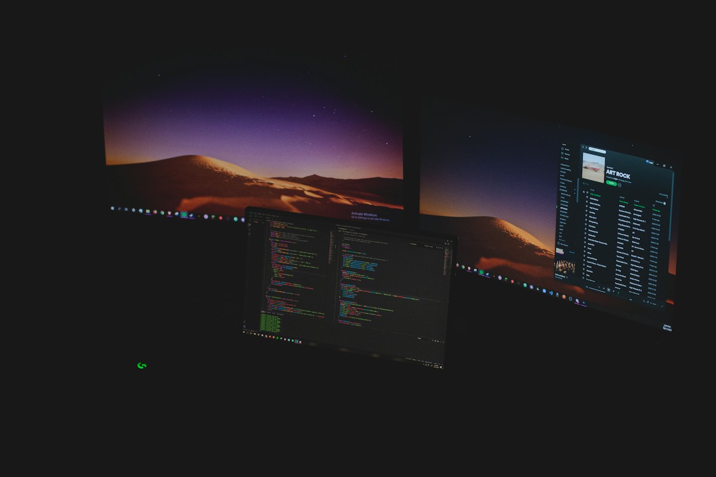 Mehrere Computermonitore, die Code und Kunstfelsen anzeigen.